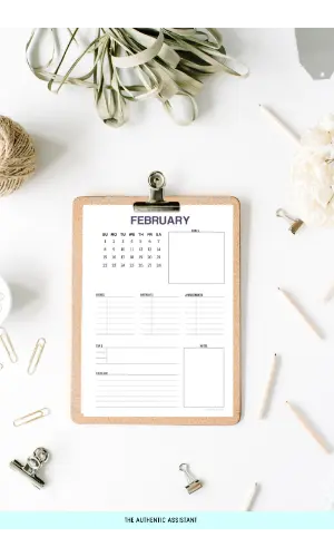 A February printable monthly planner on a clipboard resting on the desk top